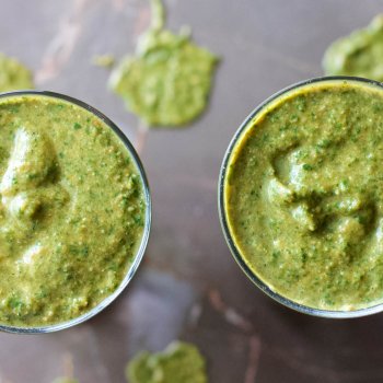Two glasses of freshly made Healthy Greens Power-Up Smoothie on a marble table.
