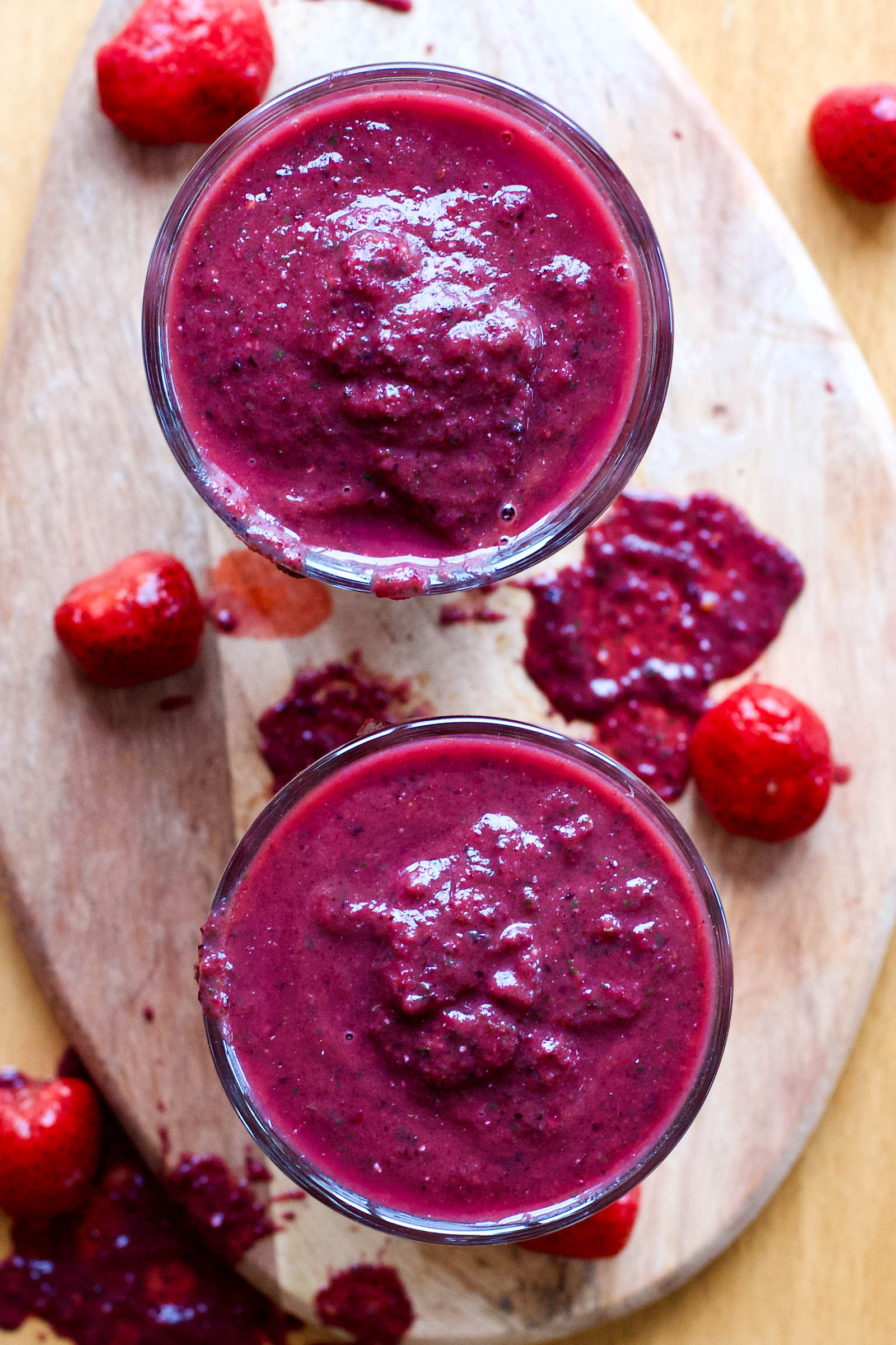 Two glasses of freshly made Berry Revitalizer Smoothie on a wooden board, top-down view