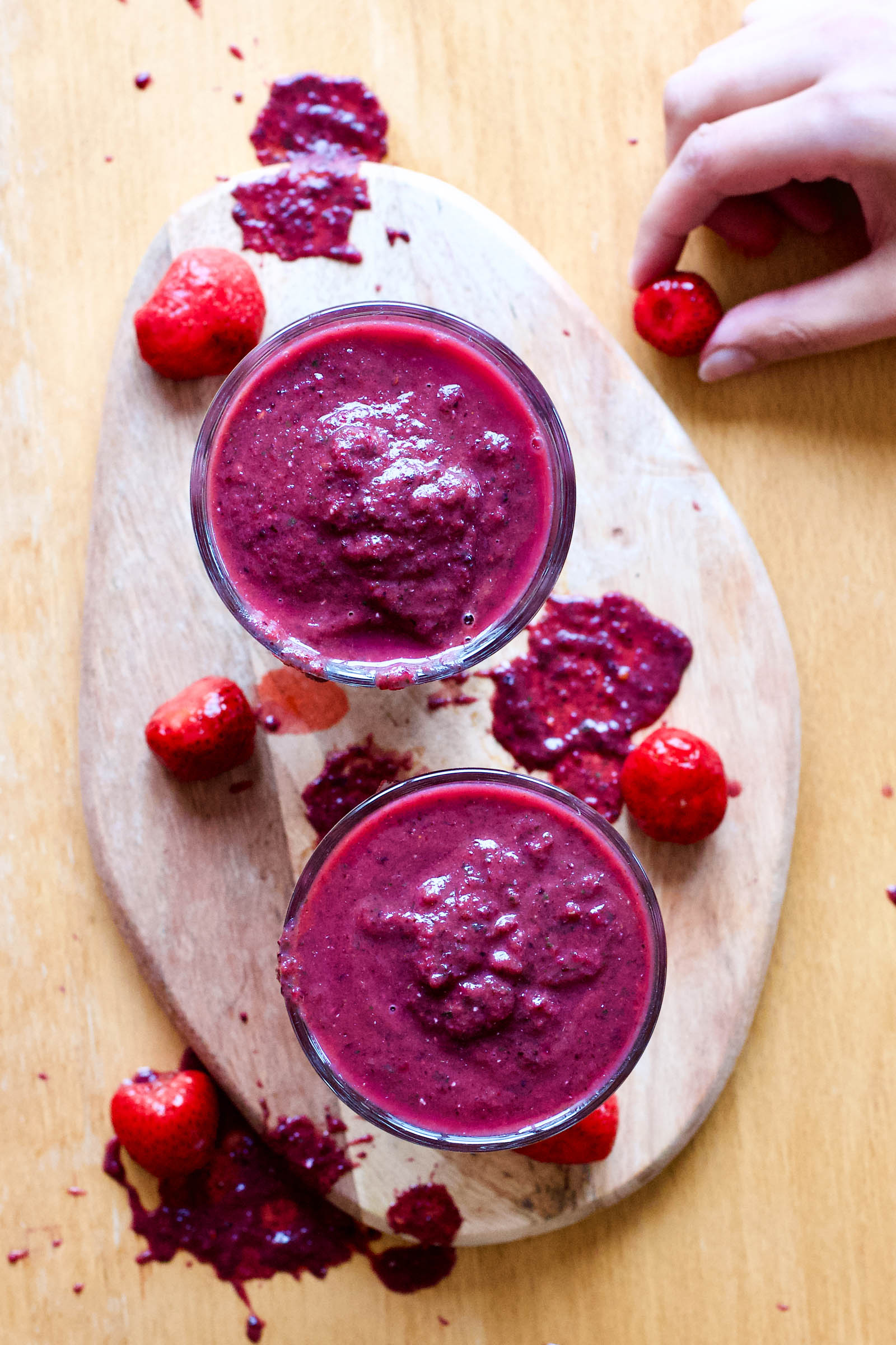 Two glasses of freshly made Berry Revitalizer Smoothie on a wooden board, top-down view