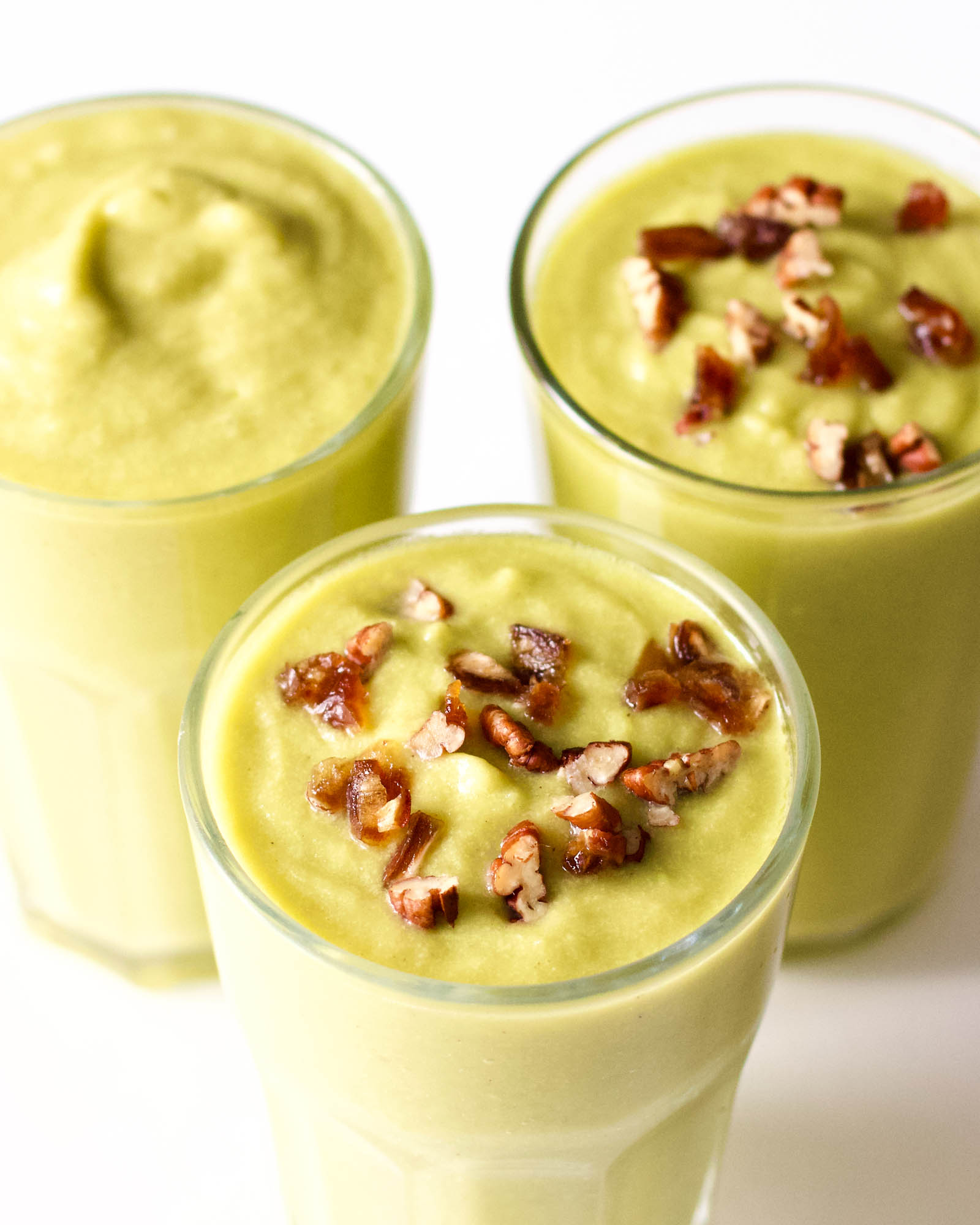 Three glasses of Mad Mango Smoothie on a white table