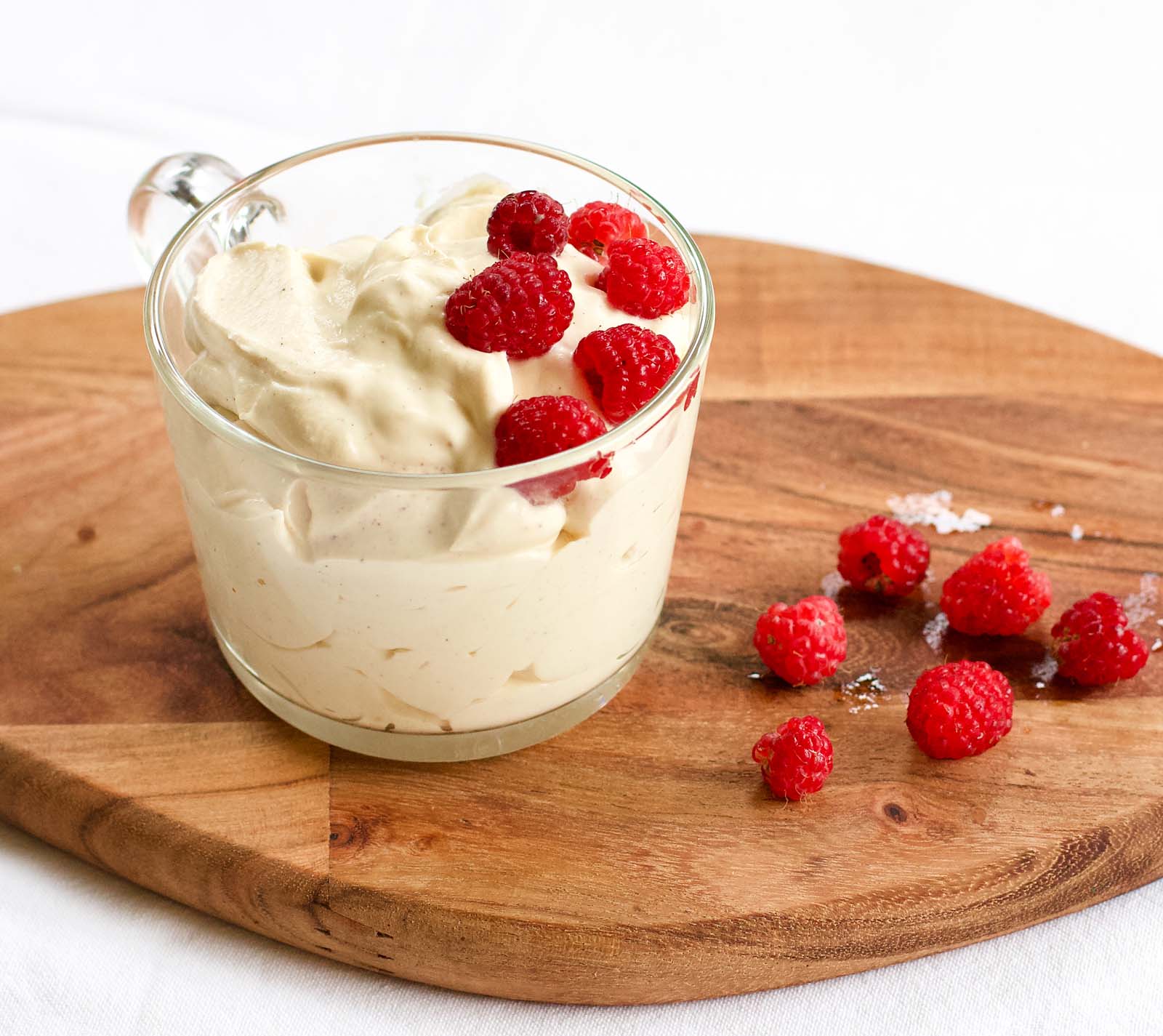 Homemade Raspberries Whipped Cream Dessert with fresh raspberries on the side, on a wooden board
