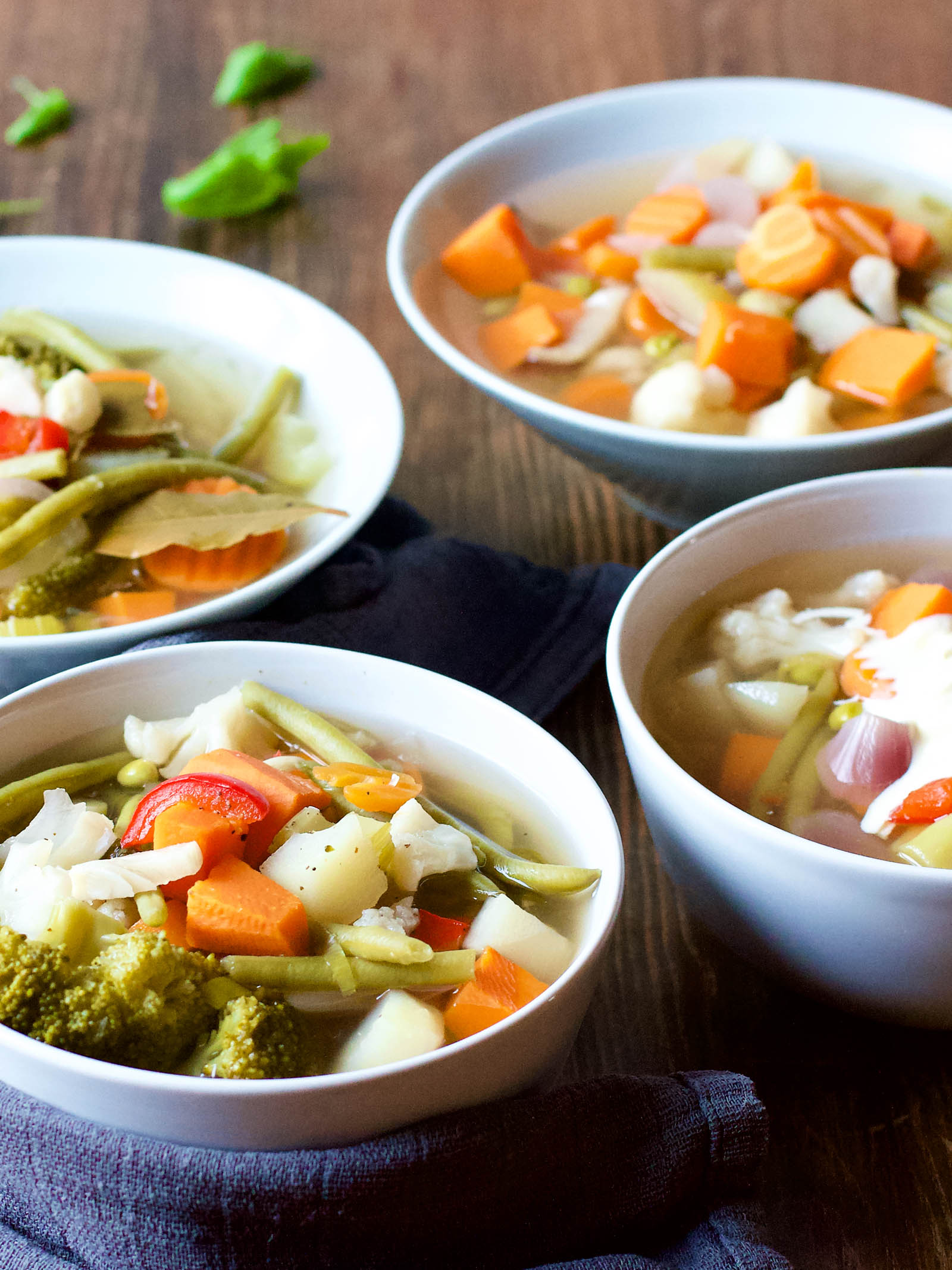 Close-up with four bowls of Spicy Vegetable Sour Soup on a wooden table