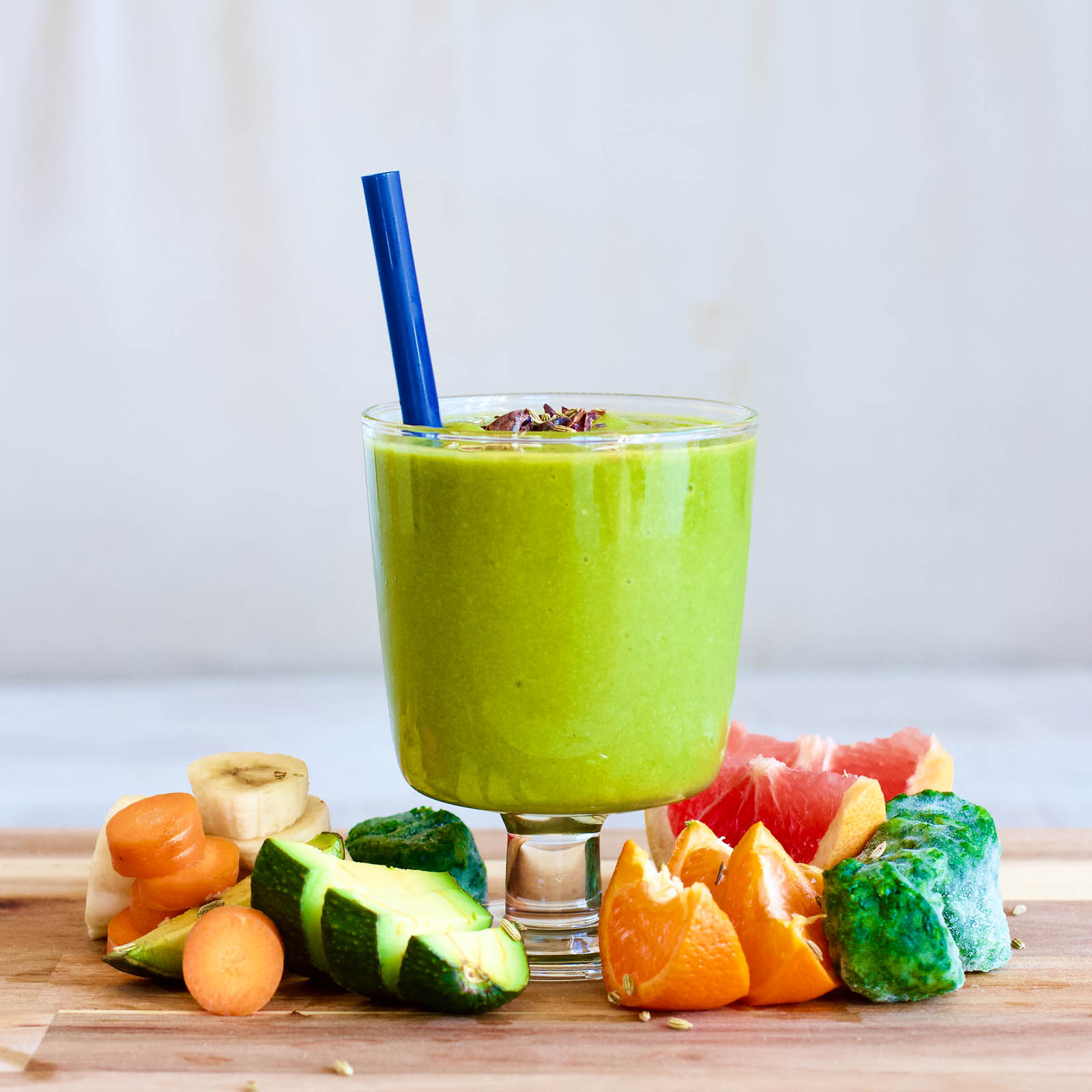 One serving of Green Smoothie Rocket with Avocado, Spinach and Grapefruit surrounded by plants on a coffee table