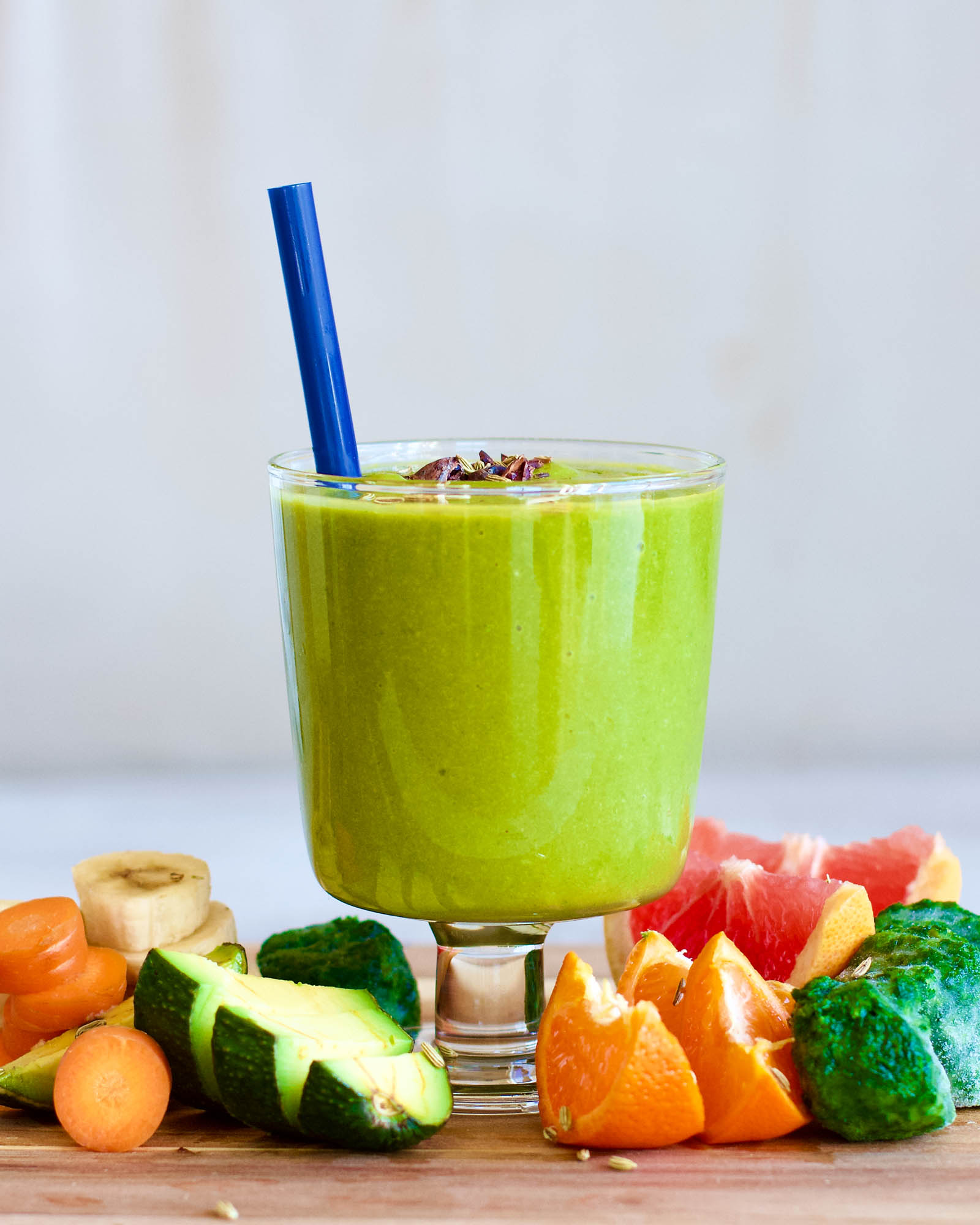 Glass of Green Smoothie Rocket with Avocado, Spinach and Grapefruit surrounded by plants on a coffee table, close-up shot