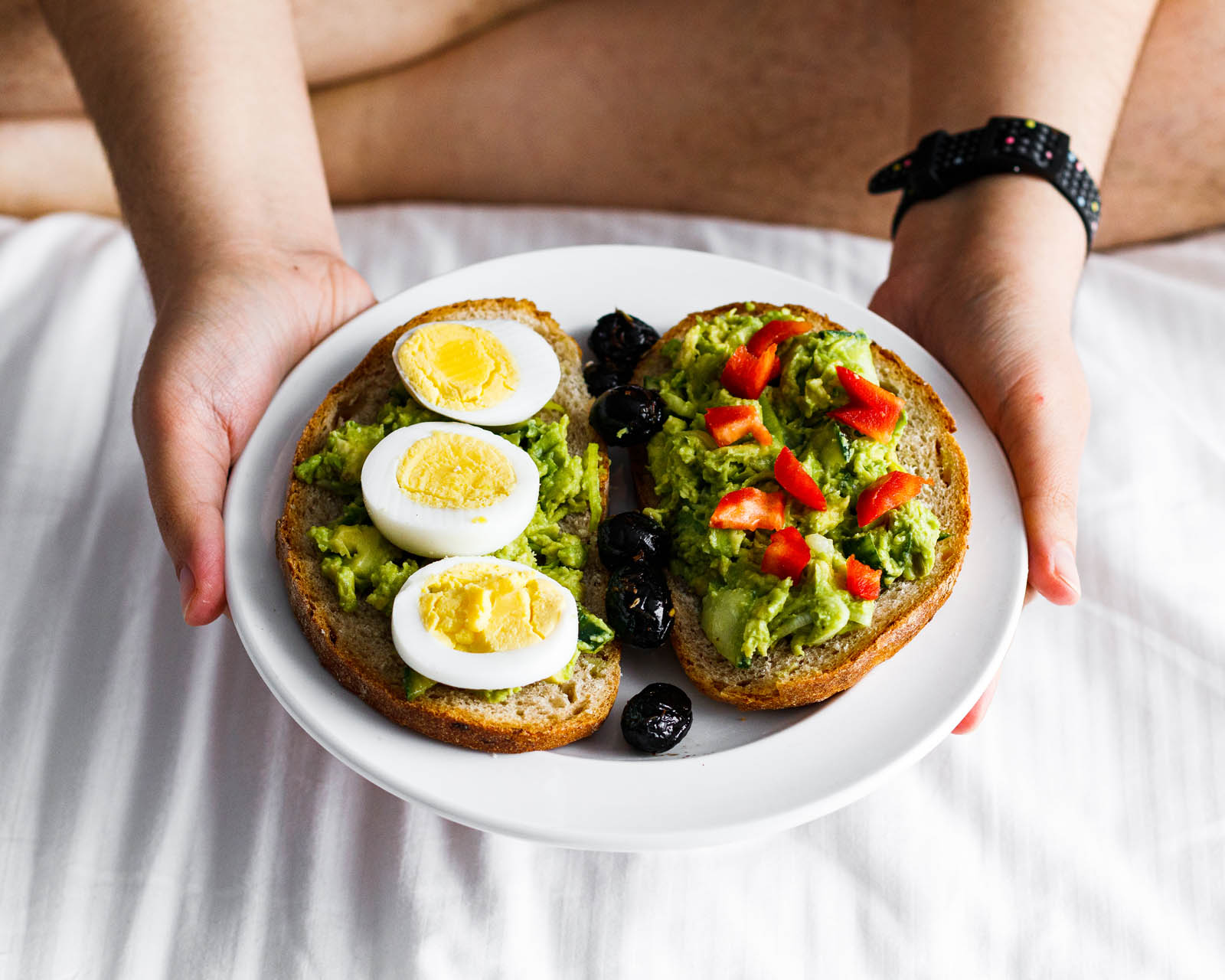 Plate with single serving of Healthy 5-Minute Guacamole on Bread, front view and in-hand presentation
