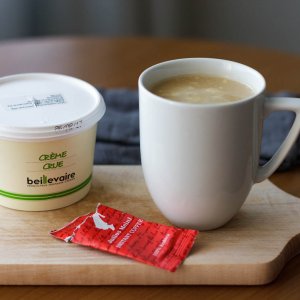 Mug with freshly made Keto Instant Coffee and creme crue on a wooden board