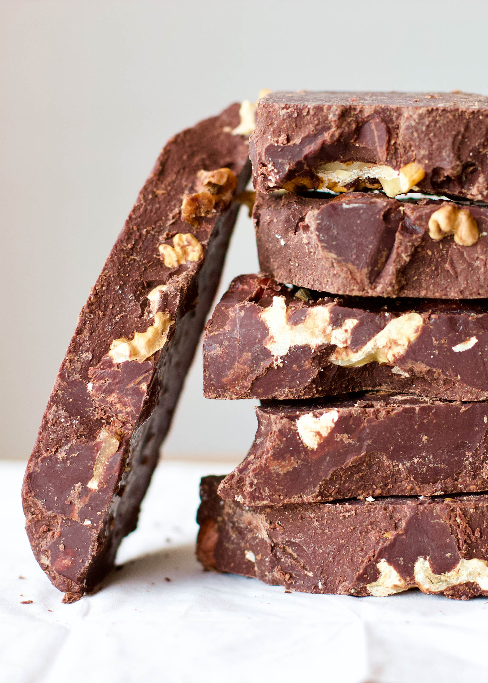 Close-up shot, stacked pieces of Homemade Dark Chocolate with Walnuts + one piece on the side