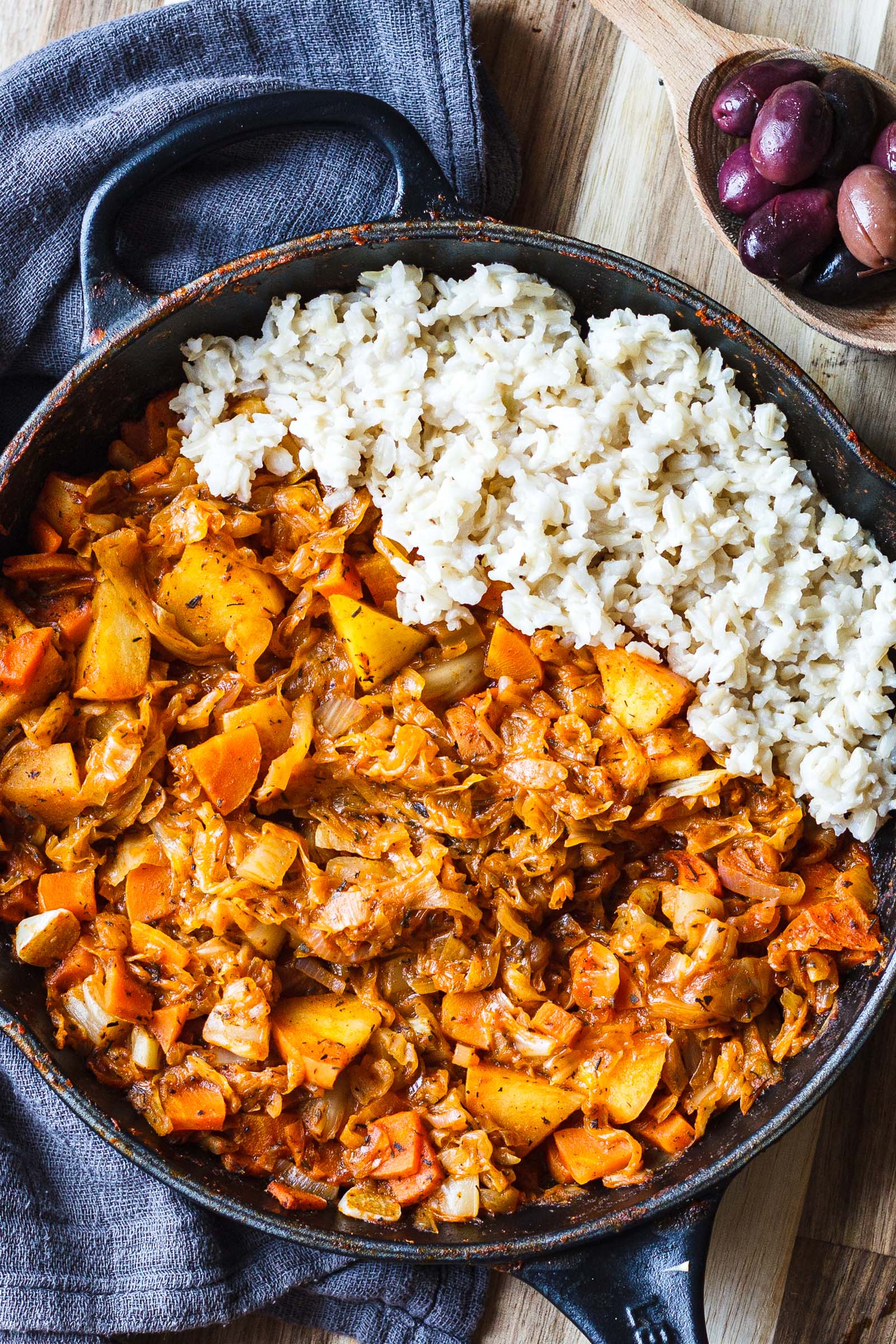 Traditional Sour Cabbage Stew in skillet with a side of white rice and kalamata olives, top-down view