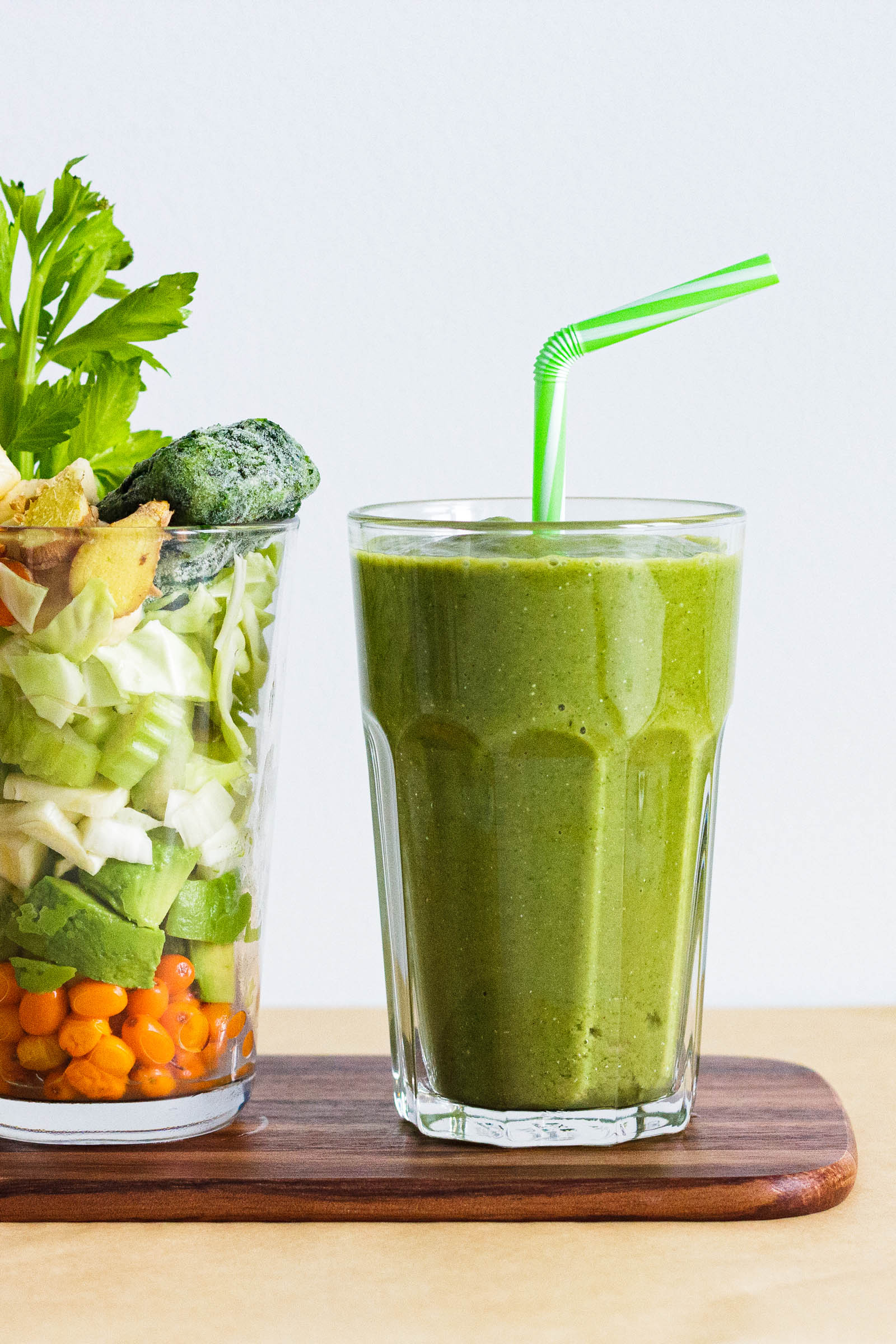 Big glass of freshly made Super Refreshing Vegetable Green Smoothie, and another glass with fresh plants on the side