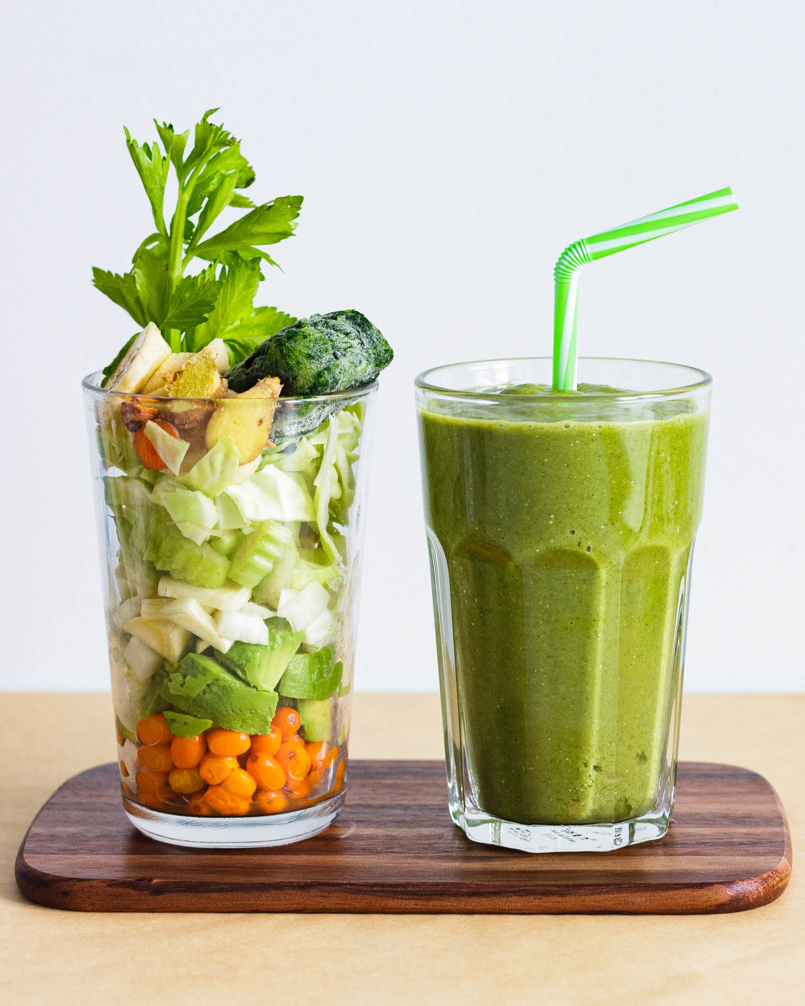 Big glass of freshly made Super Refreshing Vegetable Green Smoothie and another glass with fresh plants