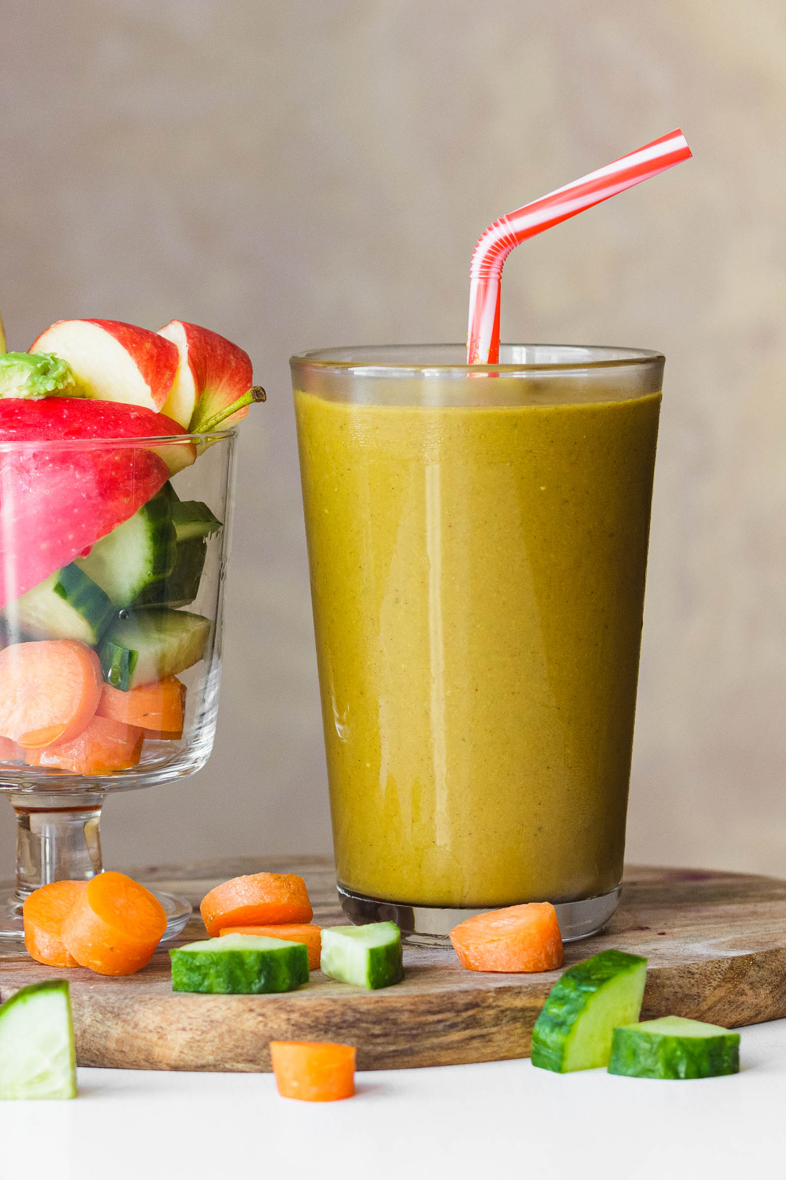 Big glass of freshly made 5-Ingredient Simple Yellow Smoothie, and another glass with fresh plants on the side