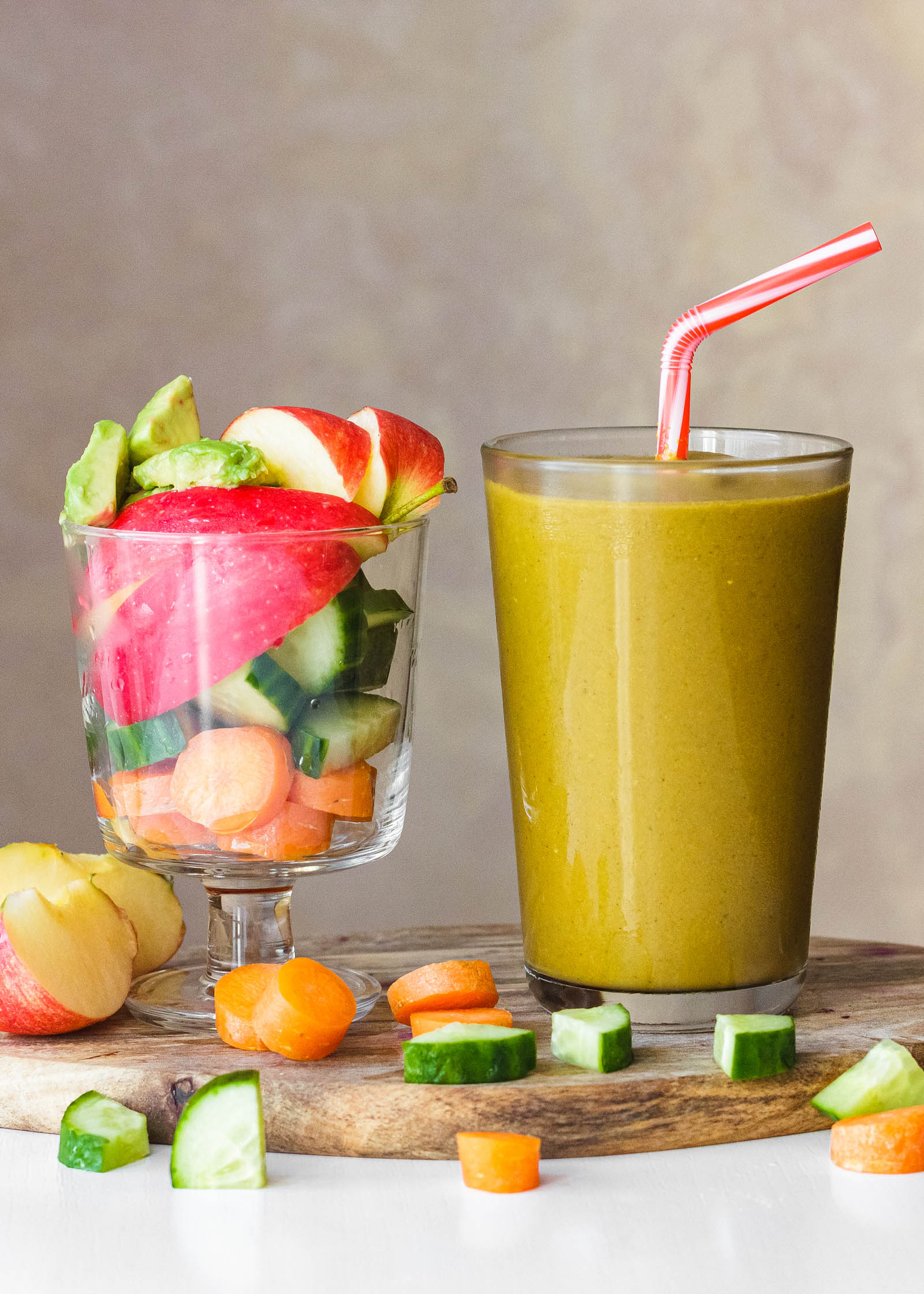 One glass of freshly made 5-Ingredient Simple Yellow Smoothie, and another glass with fresh plants