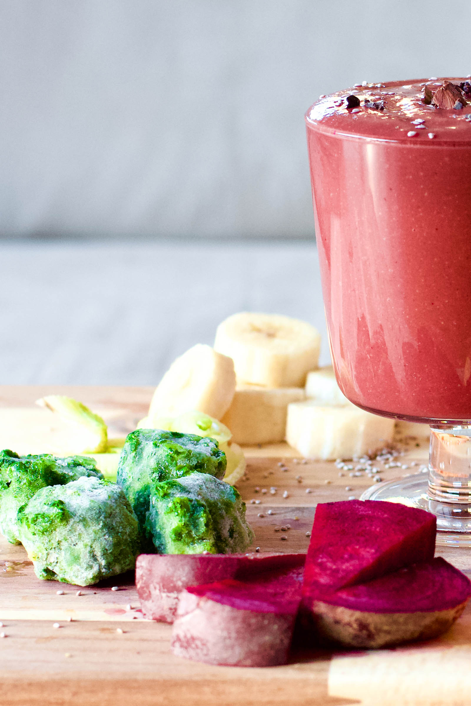 Glass of freshly made Sweet, Bitter and Spicy, Red Smoothie Rocket, surrounded by fresh plants, close-up shot