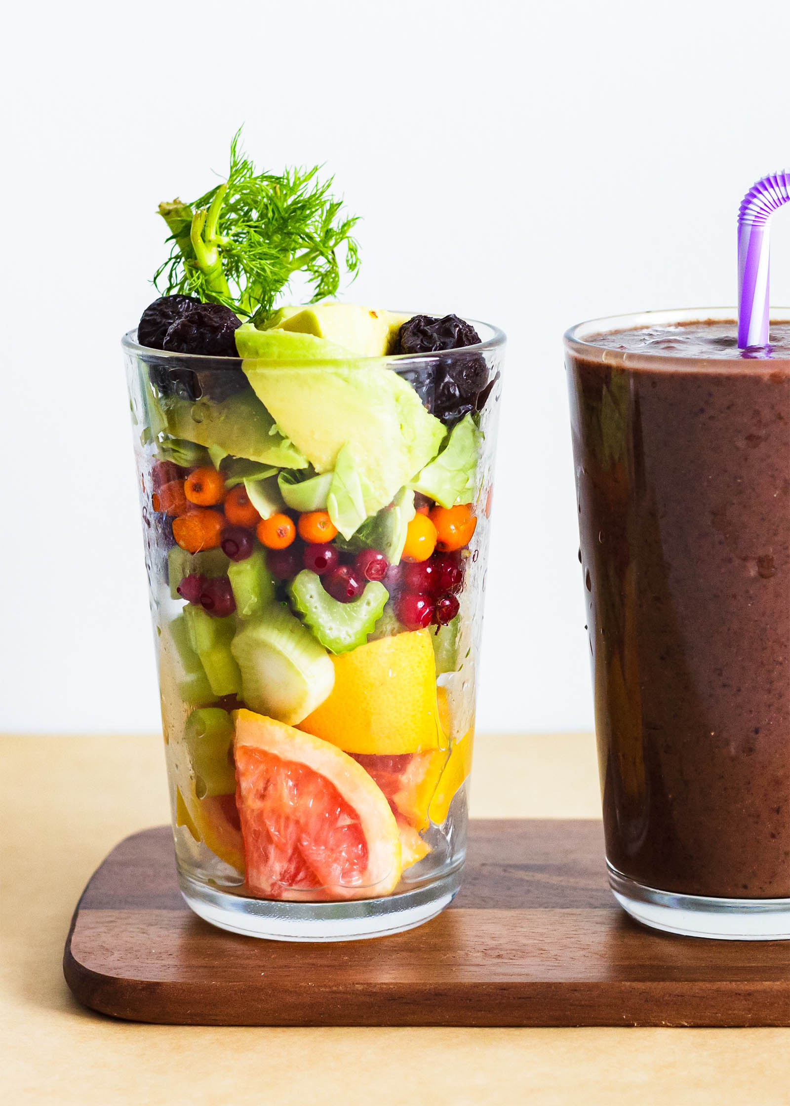 Big glass with fresh plants and another glass with Hide Your Spinach Smoothie on the side