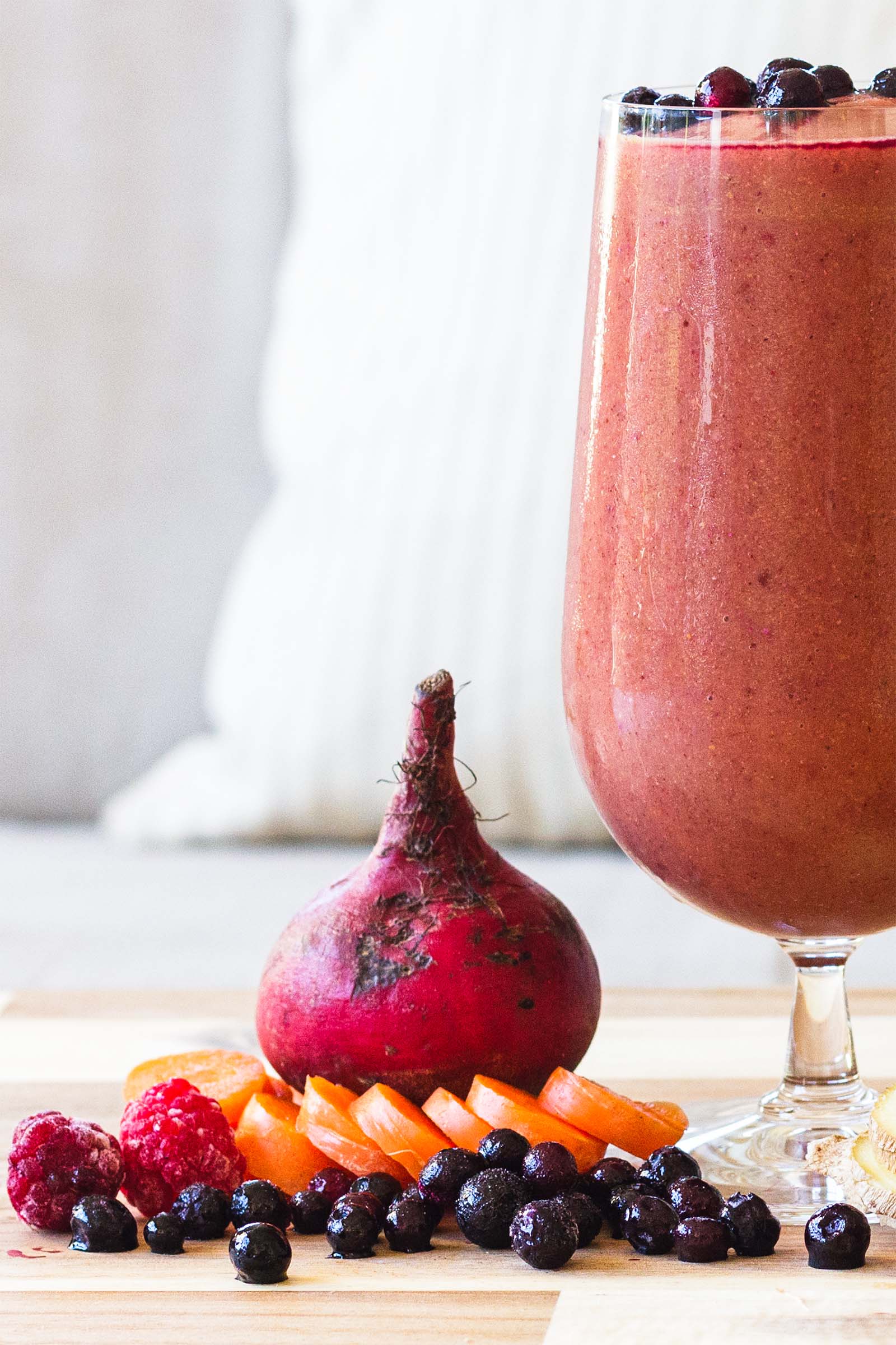 Close-up with fresh plants used for making Beet Berry Cauliflower Refreshing Fall Smoothie, and a glass of freshly made smoothie