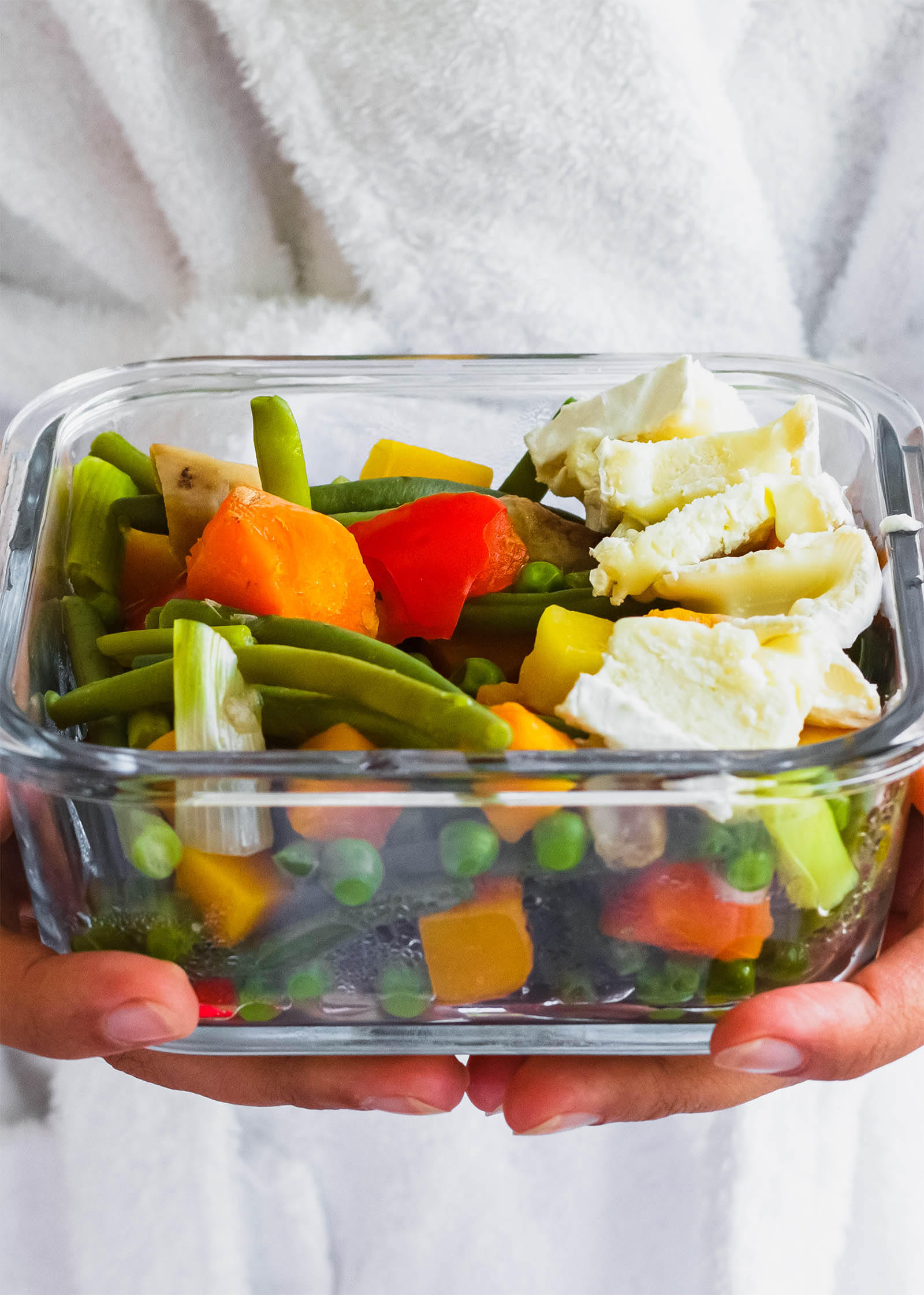 Glass tray with a serving of Salad with Steamed Vegetables and Brie Cheese, close-up shot