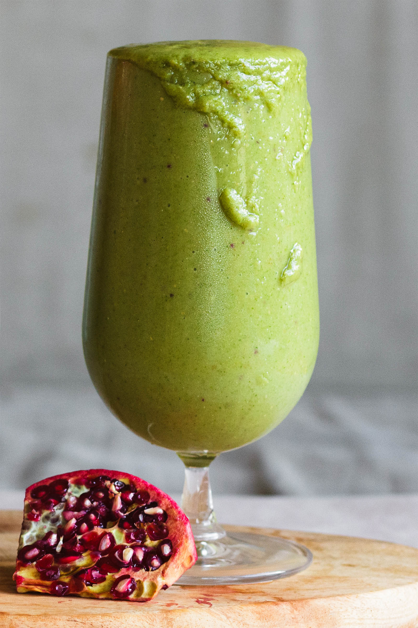 One glass of freshly made Broccoli Mango Green Smoothie Treat on a wooden board, close-up shot