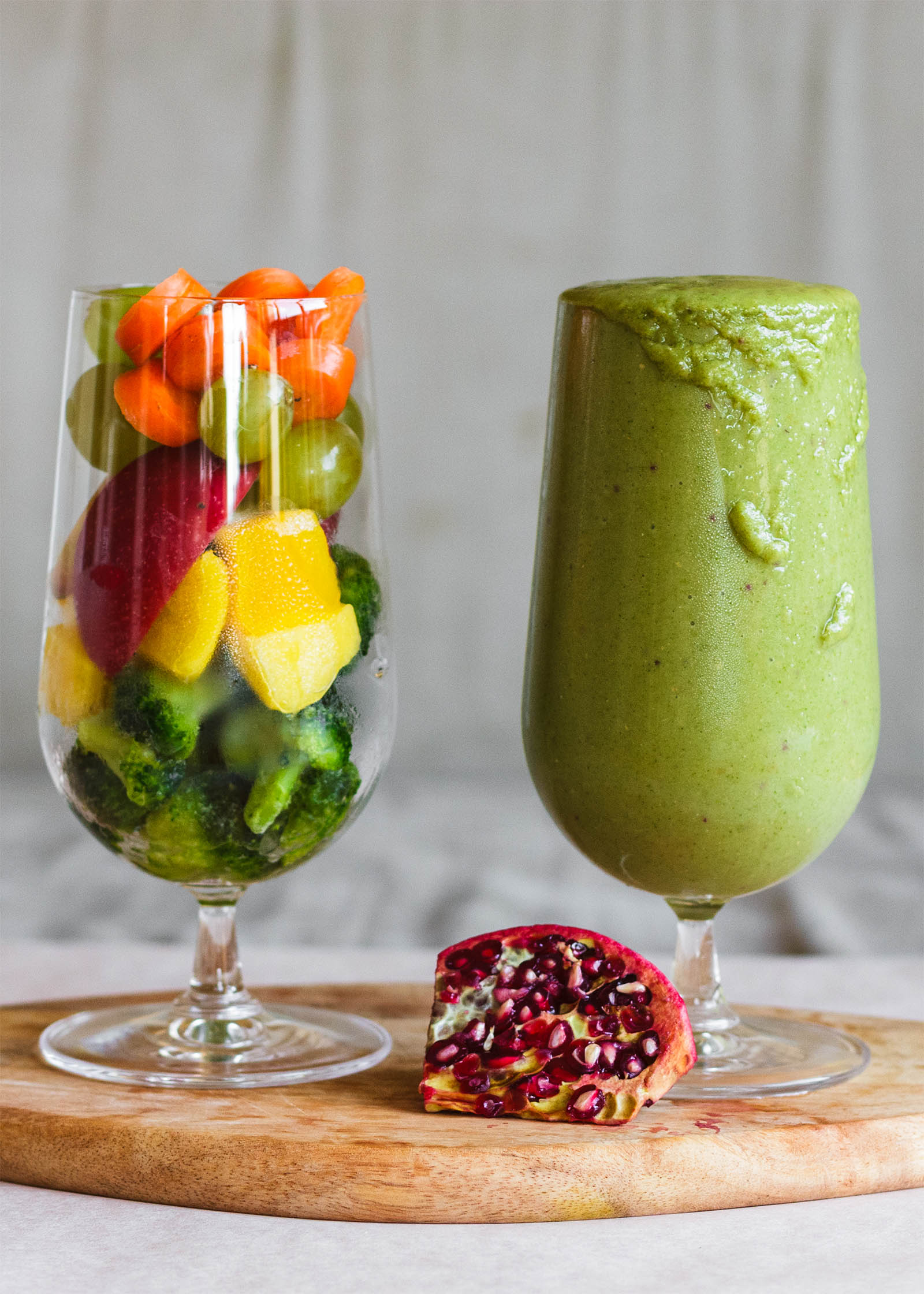 One glass of freshly made Broccoli Mango Green Smoothie Treat, and a second glass with vegetable ingredients