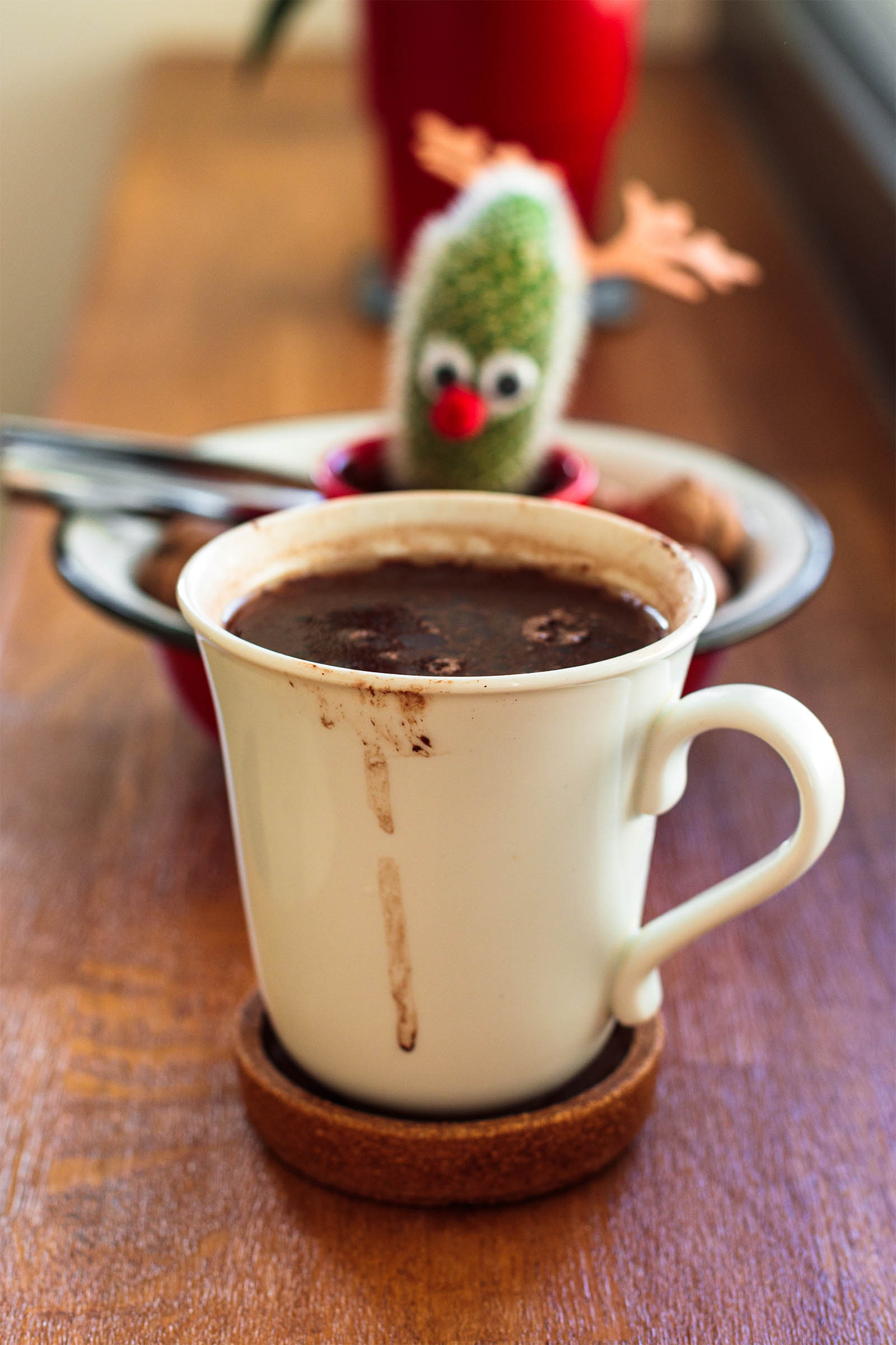 Mug with freshly made 5-Minute Vegan Hot Cocoa on a wooden table, and cactus plant in the background