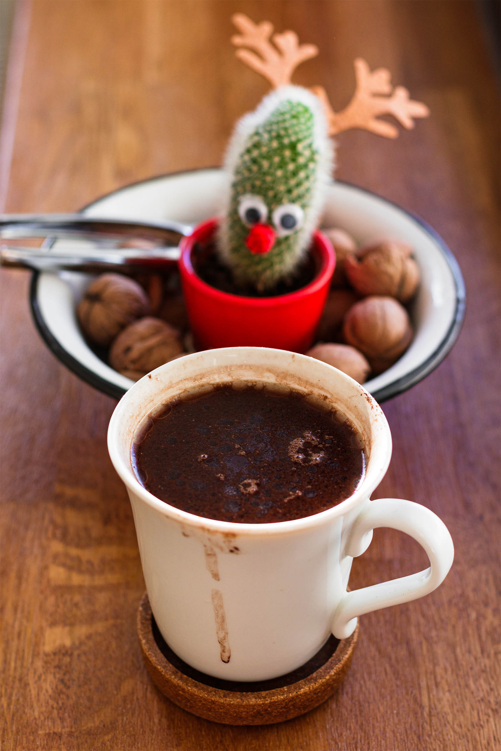 Mug with freshly made 5-Minute Vegan Hot Cocoa on a wooden table, and cactus plant in the background