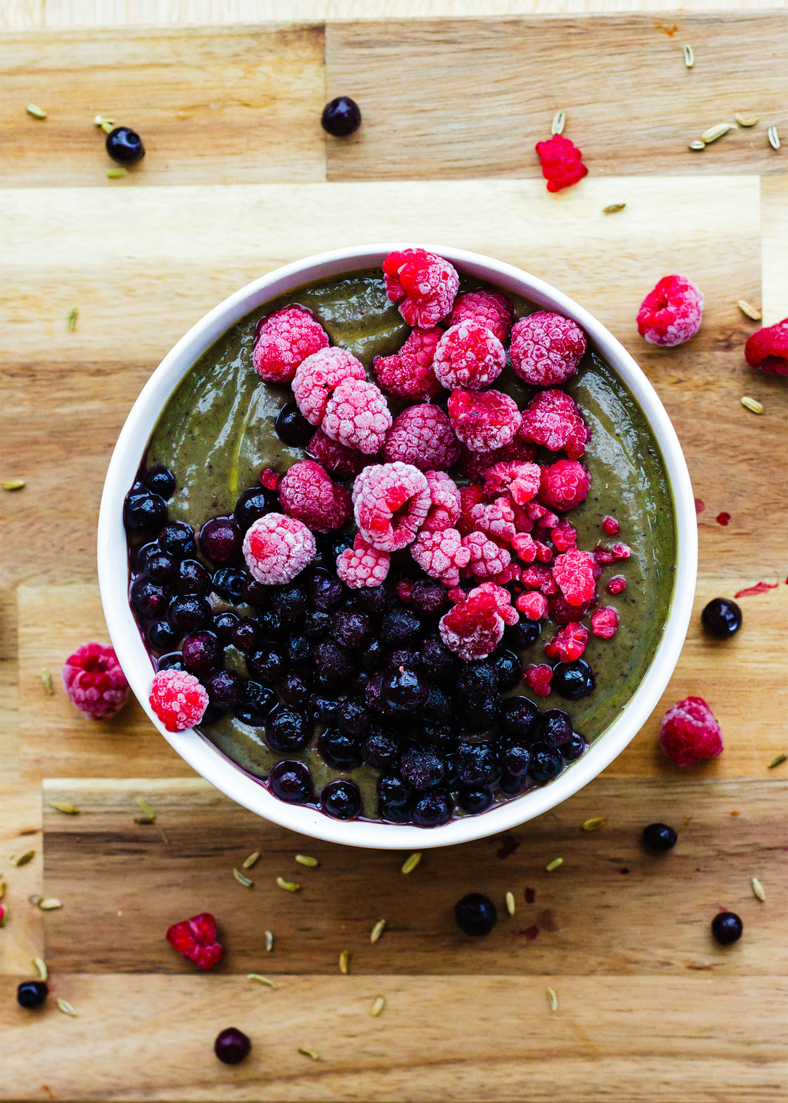 Top-down view of Avocado Spinach Blueberry Green Smoothie Bowl on a wooden board